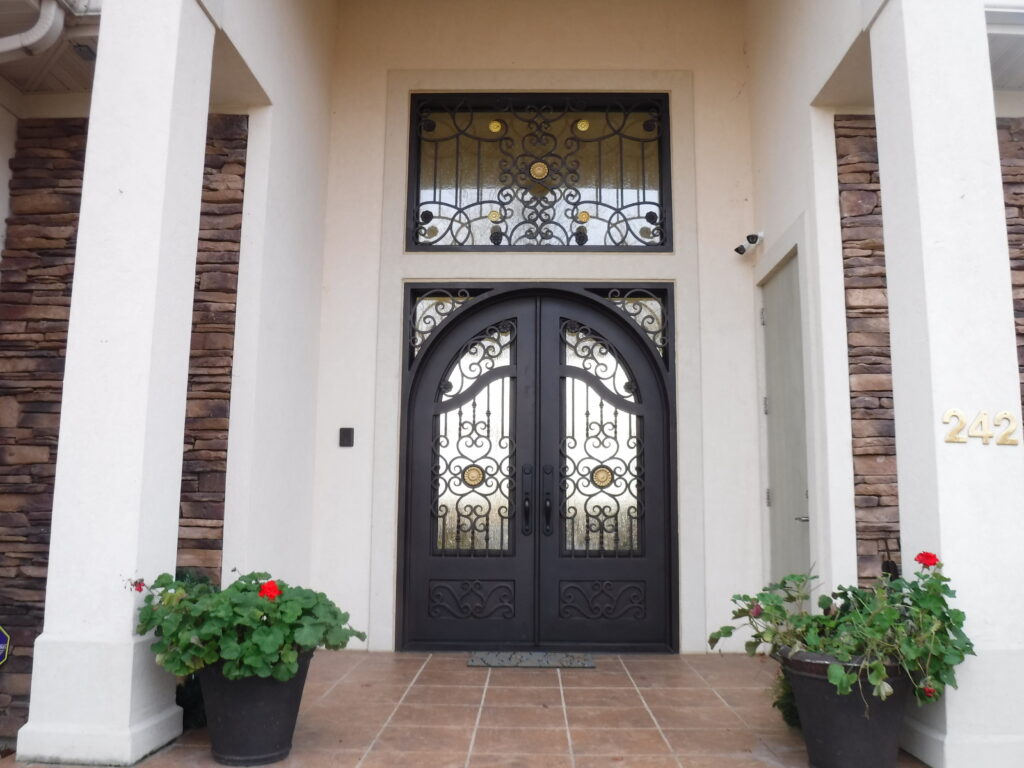 Black arched wrought iron entrance door with window above and trellis work